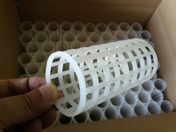 Several plastic filter tubes are packed orderly in a box and a tube is held by a hand.