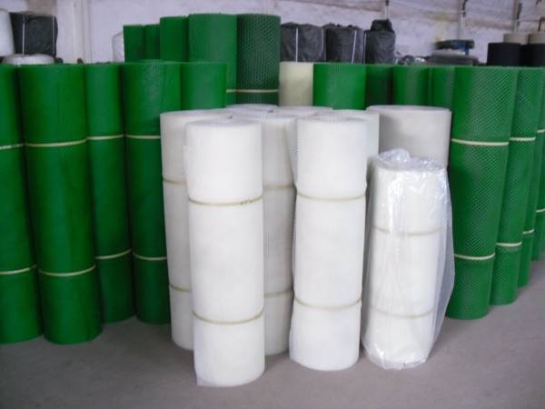 Many rolls of extruded square plastic mesh tree guards in white or green color in our warehouse.