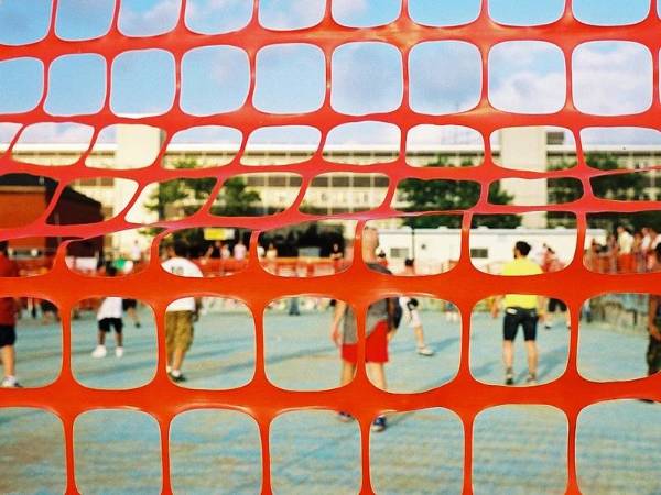 Orange plastic safety netting for sports barrier fencing and many people there