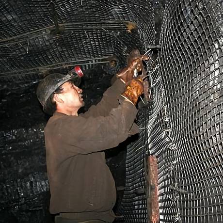 A worker is fastening black color mine bilateral stretched plastic mesh onto the roadway sidewall.
