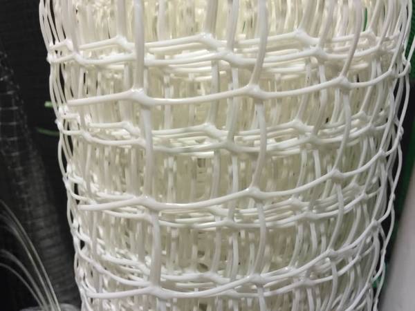 A roll of white HDPE deer fencing with square mesh holes