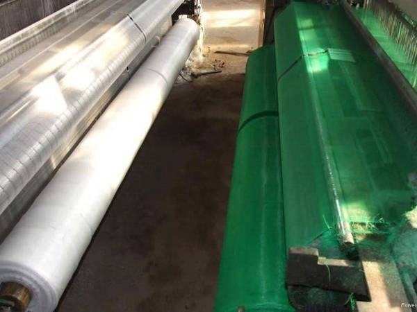 Green and white plastic insect screens are woven by screen machine